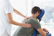  Massage therapist giving back massage to employee at the work place